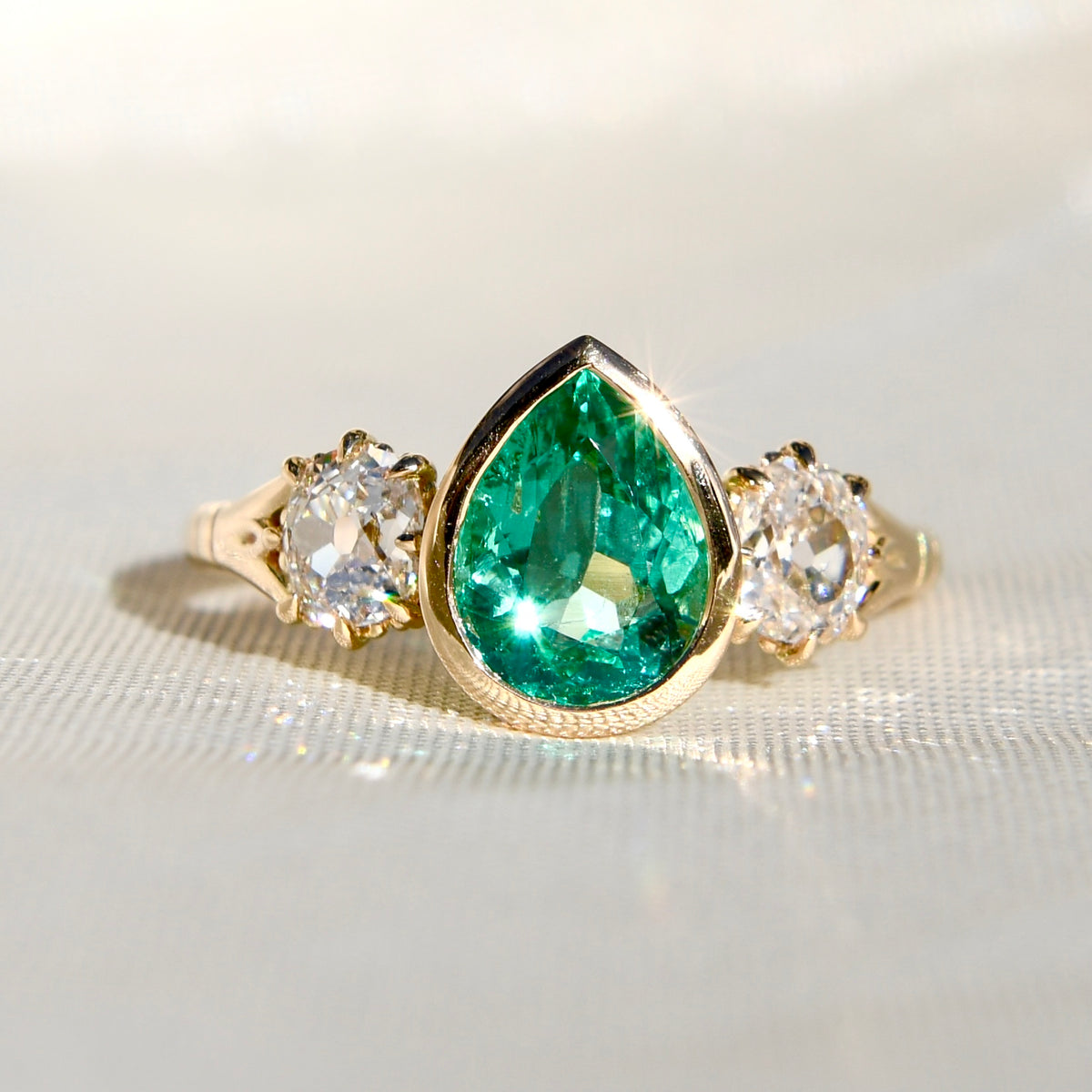 1.34 ct Colombian pear cut emerald and old mine cut diamond three stone ring