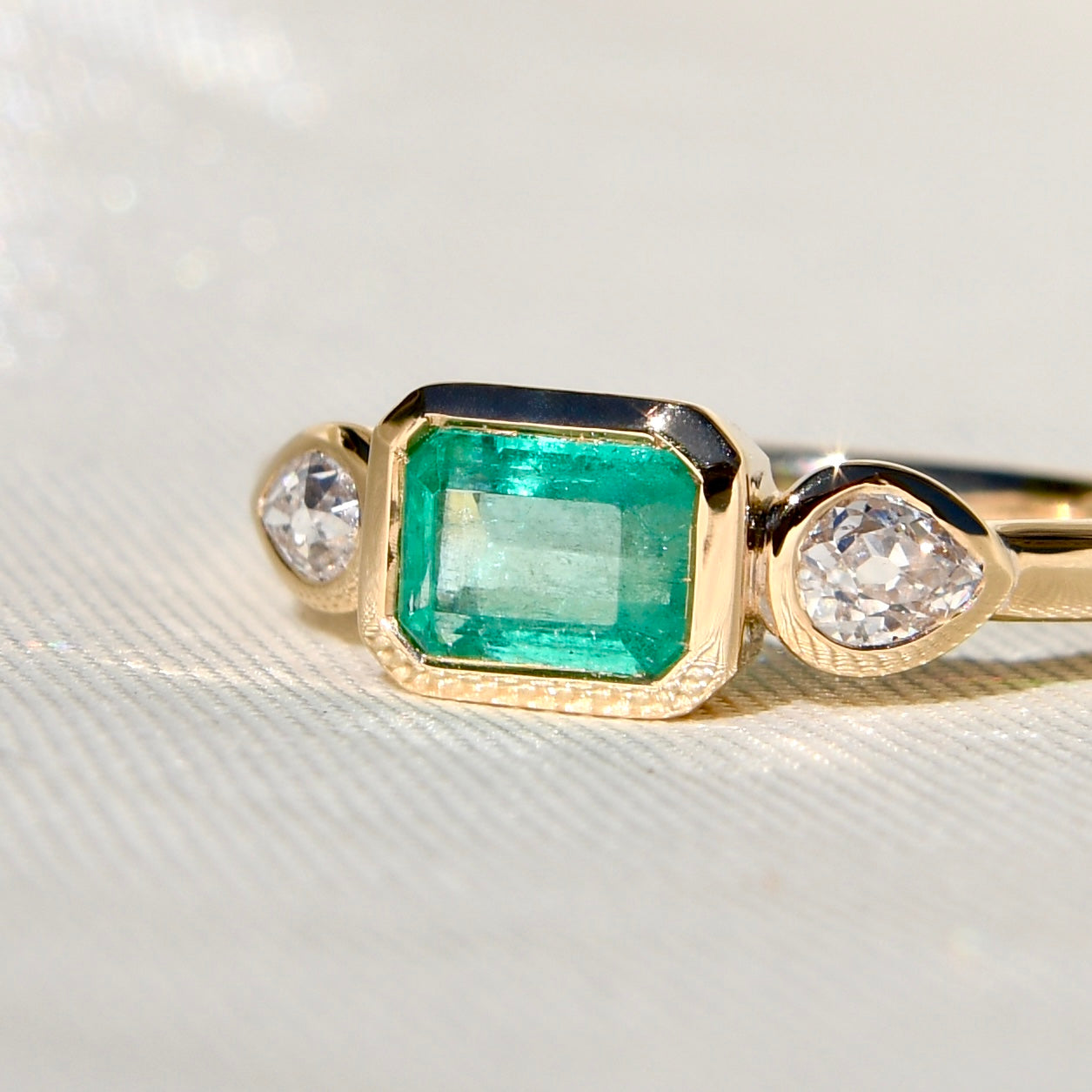 0.69 ct Colombian emerald and old pear cut diamond three stone ring