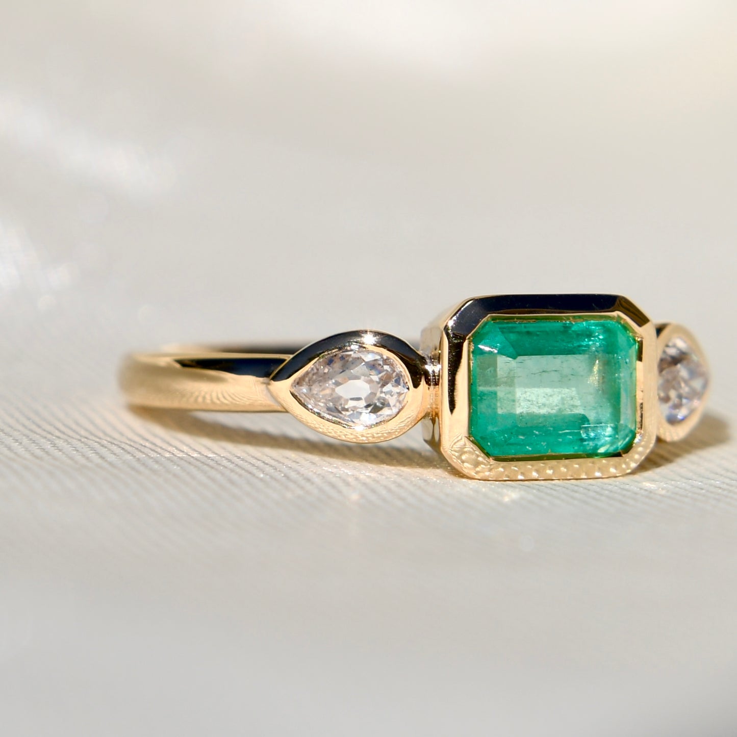 0.69 ct Colombian emerald and old pear cut diamond three stone ring